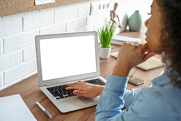 A female student wearing a blue shirt is pictured working at a laptop.